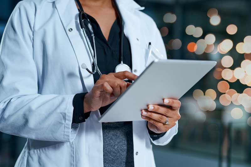 person in lab coat with tablet